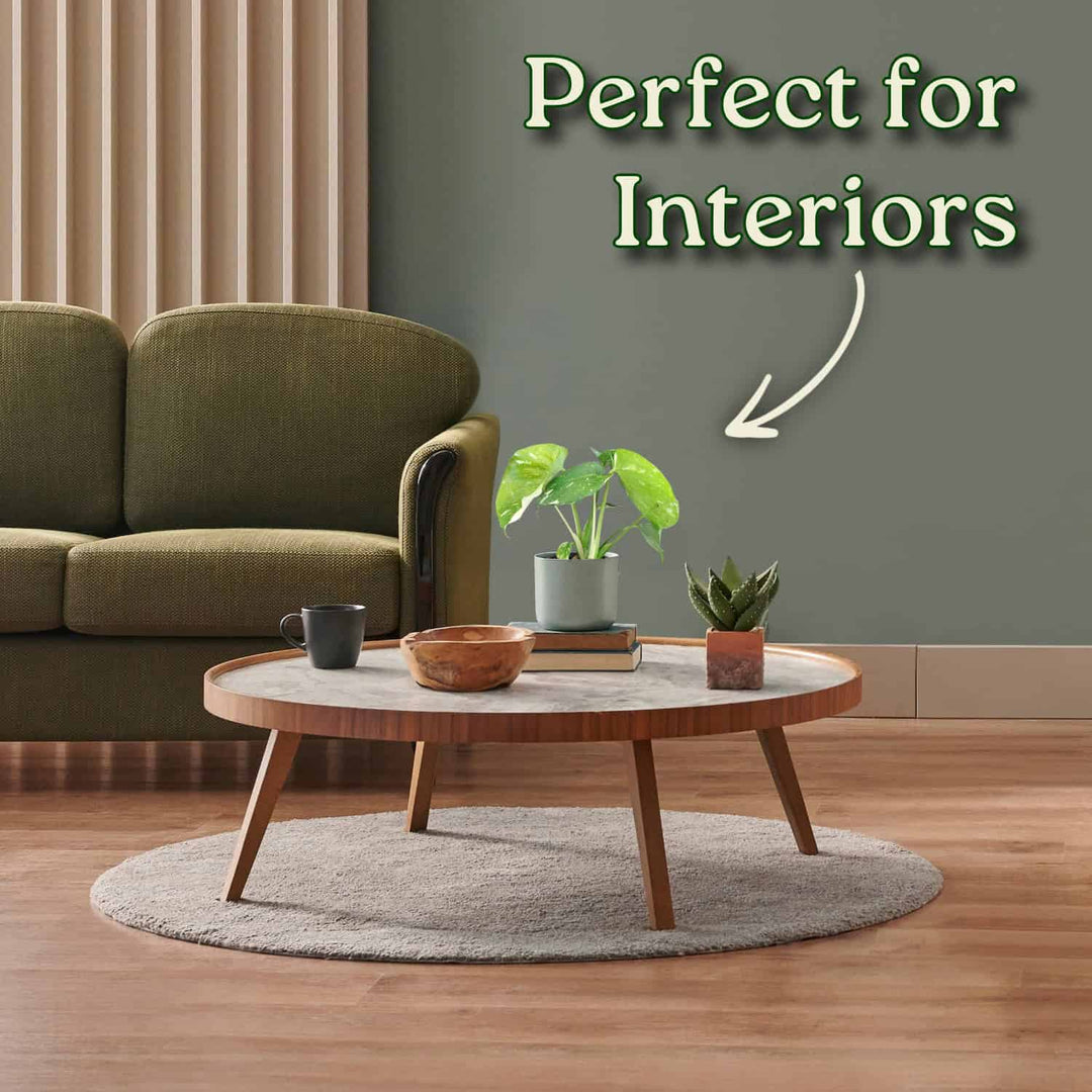 Living room with a green sofa, round wooden coffee table, and decorative items. #size_1-pint